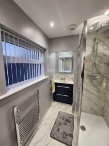 a bathroom with a shower and a sink at House on the Furrows in Luton