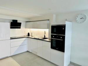 a kitchen with white cabinets and a clock on the wall at Appartement Le Léman in Excénevex