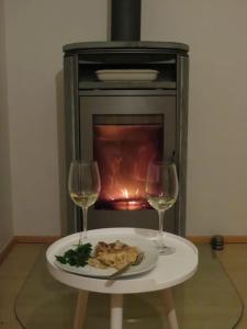 einen Teller mit Essen und zwei Weingläsern vor dem Kamin in der Unterkunft Panoramablick in Stiefenhofen