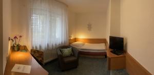 een kleine kamer met een bed, een stoel en een televisie bij Cascade in Stuttgart