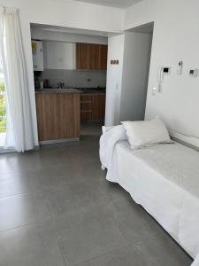 a bedroom with a white bed and a kitchen at Ninfas Plaza in Puerto Madryn