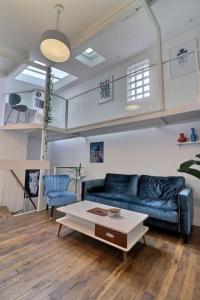 Una sala de estar con un sofá azul y una mesa de café. en Unique loft apartment Located 15 minutes from the Champs Élysées, en Saint-Ouen