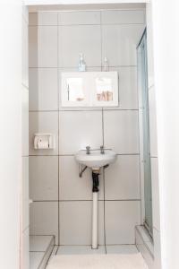 a white bathroom with a sink and a mirror at Nkosazana Guest House in Durban +40 photos