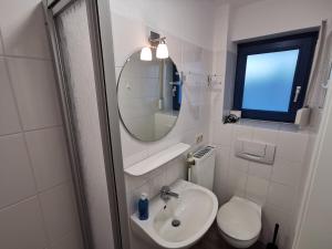 uma casa de banho com um lavatório, um espelho e um WC. em Strandsegel em Horumersiel