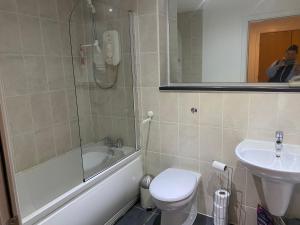 uma casa de banho com um WC, um lavatório e um chuveiro em City Centre 2 bedroom apartment, secure parking. em Glasgow