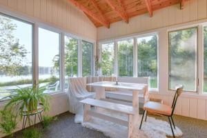 un porche cubierto con mesa, sillas y ventanas en Scenic & Serene Lakefront Cottage With Wood Stove en Crivitz