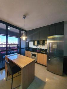 a kitchen with a table and a stainless steel refrigerator at Estúdio Confortável no 12º Andar do Ed. Vertigo in Campo Grande