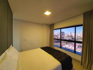 a bedroom with a bed and a large window at Estúdio Confortável no 12º Andar do Ed. Vertigo in Campo Grande +8 photos