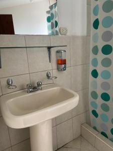 lavabo blanco en un baño con ventana en Blue house La Floresta, en Quito