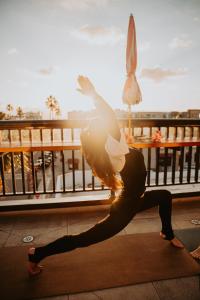 a woman doing a yoga pose in front of a balcony at The Brick Boutique Hotel in Oceanside