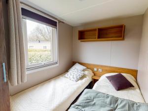 um pequeno quarto com 2 camas e uma janela em Mobilhome NEUF Mar estang Accès Plage em Canet-en-Roussillon