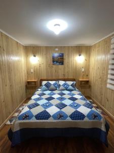 1 dormitorio con 1 cama blanca y azul a cuadros en Cabañas Rukafun 2 en Pucón