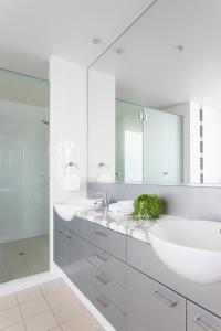 a white bathroom with two sinks and a shower at Aspect Caloundra in Caloundra