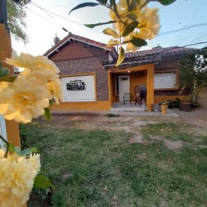 una casa con flores amarillas delante de ella en Complejo Los Platanos en General Alvear