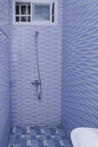 baño de azulejos azules con ducha y ventana en Maison Bethel Kpogan Afidenigba 