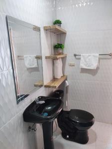 uma casa de banho com um WC preto e um lavatório. em ROOM COLIBRÍ - La Casa de Eros em Ayampe