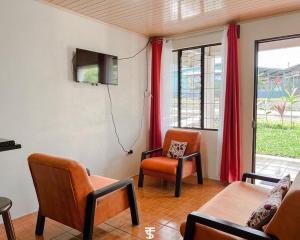 a living room with a couch and chairs and a tv at Villa Rincón del Arenal in Fortuna