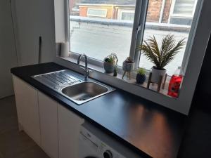 um balcão de cozinha com um lavatório e uma janela em Primrose Stays - 3 bedroom House em Stoke-on-Trent