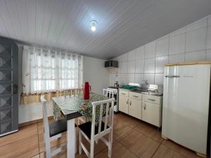 a kitchen with a table and a white refrigerator at Casa Suzena 300 metros Parque e Praias in Penha