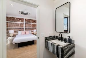 a bedroom with a bed and a sink and a mirror at The Brick Boutique Hotel in Oceanside