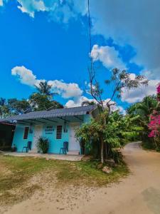 un edificio azul con un árbol delante de él en Bonda Room Stay Langkawi, en Pantai Cenang