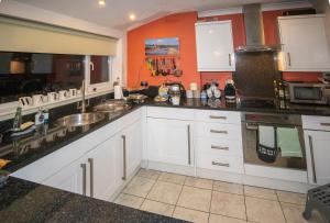 una cocina con armarios blancos y una pared de color naranja en No. 2 Watch House, en Dawlish