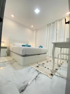 a white bedroom with a bed and a table at Modern appartment Palma in Palma de Mallorca