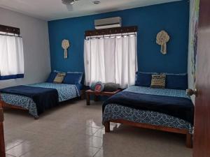 Habitación con 3 camas y pared azul. en Casa Chen-Huaye, en Isla Mujeres