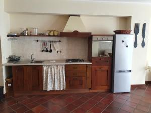 a kitchen with wooden cabinets and a white refrigerator at Casa La Ferula apt1 vicino al mare e Taormina in SantʼAlessio Siculo