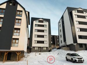 a car parked in a parking lot in front of two buildings at Nomad Jahorina in Jahorina