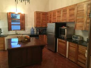 cocina con armarios de madera y nevera de acero inoxidable en Private Restored Hacienda With Its Own Cenote, en Espita