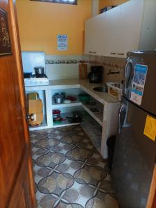 una pequeña cocina con armarios blancos y nevera. en La Casa De Lili, en Olón