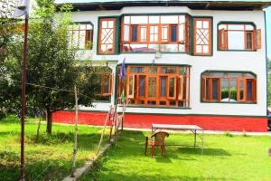 a red and white house with a table in the yard at Hotel Gulsitara-Kunzer Gulmarg in Gulmarg