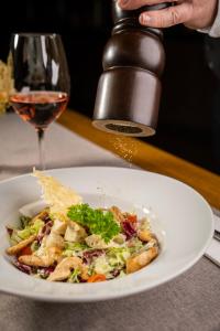 einen Teller mit Essen und ein Glas Wein in der Unterkunft Hotel OTP Birkenhof in Bad Kleinkirchheim