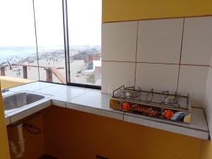 a kitchen with a stove and a sink and a window at Arica Surf & Beach House in Arica