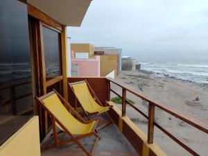 two yellow chairs sitting on a balcony overlooking the beach at Arica Surf & Beach House in Arica