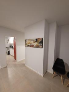 Habitación blanca con una silla negra y una pintura en la pared en Departamento nuevo con seguridad y pileta ,en villa allende a 15 del centro de Córdoba en Villa Allende