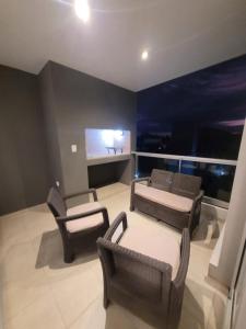 a living room with chairs and a couch and a tv at Departamento nuevo con seguridad y pileta ,en villa allende a 15 del centro de Córdoba in Villa Allende