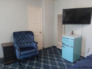 a room with a blue chair and a television at THE NEW STAR MOTEL - 1950s Extended-Stay Lodging and Retreat Center in Moreno Valley