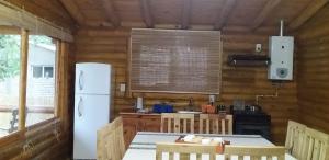 eine Küche mit einem weißen Kühlschrank und einem Tisch in der Unterkunft Cabañas Las Acacias in Colonia Las Rosas