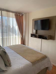 1 dormitorio con 1 cama y TV de pantalla plana en CentriK Location Apartments Encomenderos 200, en Santiago