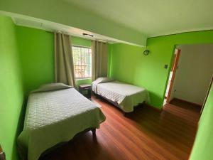 a green room with two beds and a window at Casa cercana a playa Los Vilos in Los Vilos