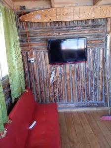 a living room with a red couch and a tv on a wall at el gitano feliz in Laguna Verde