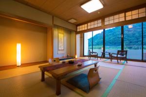 Habitación con mesa, sillas y ventanas. en Koderaso en Himeji