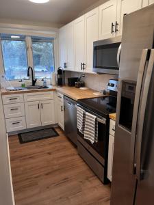 uma cozinha com electrodomésticos de aço inoxidável e armários brancos em Newly Remodeled Mid-Century Modern Lake Condo em Lake Geneva