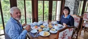 a man and a woman sitting at a table with food at Panorama Green View Hotel Nuwara Eliya in Nuwara Eliya