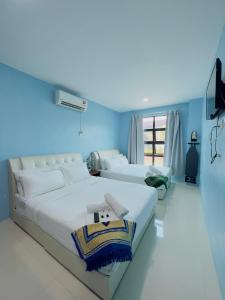 twee bedden in een kamer met blauwe muren bij Noor Boutique Hotel in Kuala Perlis