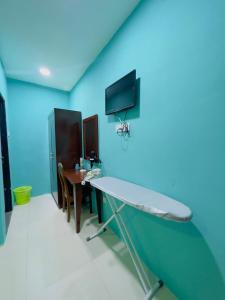 a room with a blue wall with a table and a tv at Noor Boutique Hotel in Kuala Perlis