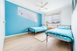 um quarto azul com duas camas e uma janela em Clifton on Charles em Iluka