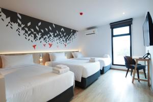um quarto com 2 camas e uma secretária com uma cadeira em KOO HOTEL em Ban Bang Talat